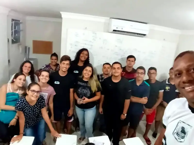Selfie do professor com a turma reunida diante do quadro com anotações