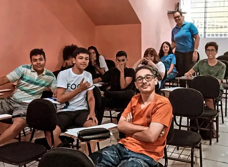 Alunos do Foco sentados nas carteiras da sala de parede laranja